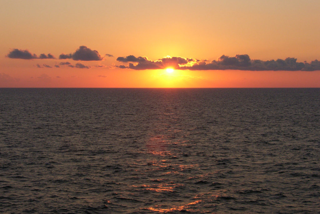 Een ondergaande zon boven een kalme zee. Symboliseert het loslaten ofwel ontspanning, één van de basis-technieken van de Davis-methode.